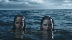 2 mermaids with their heads out from the water