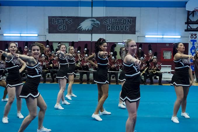 The cheerleaders are dancing on the ground.