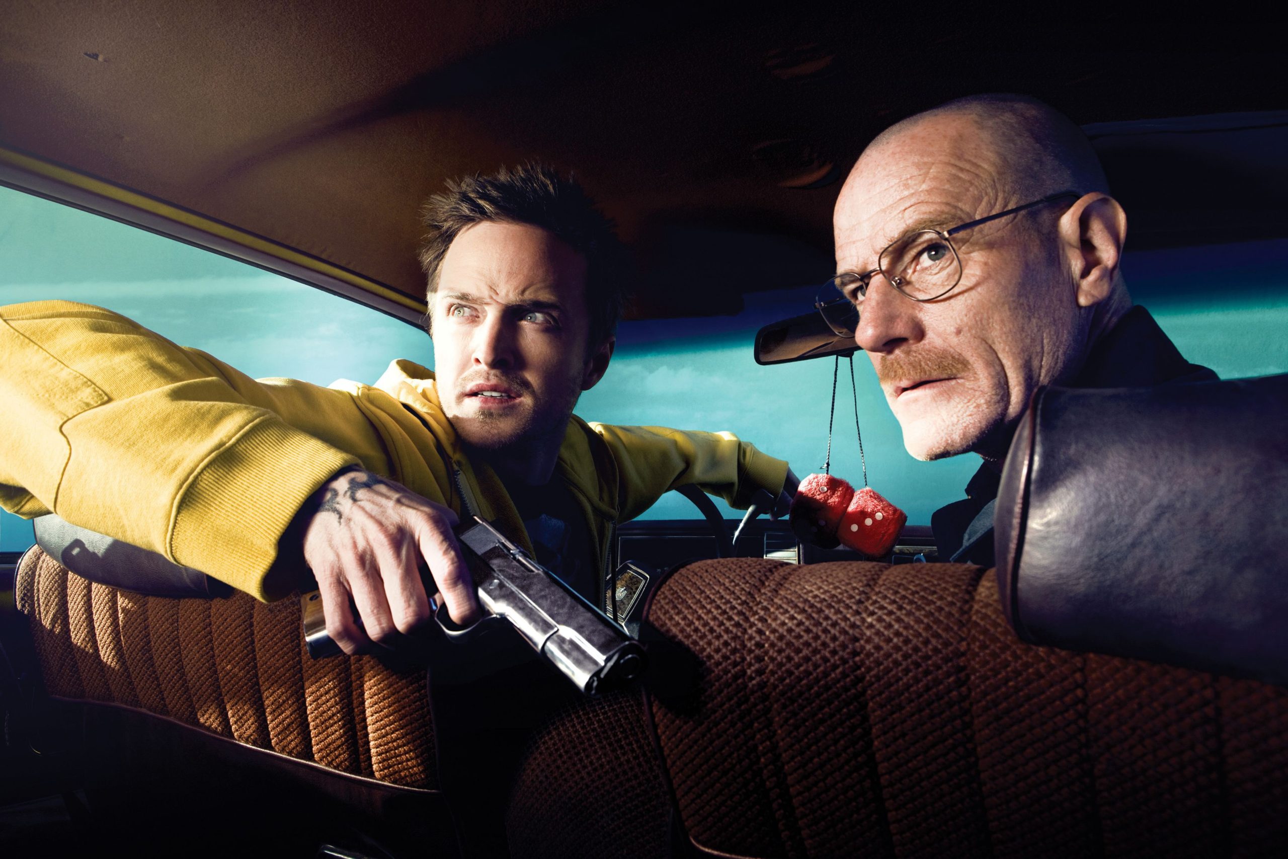 Jesse Pinkman is holding a gun and sitting with Walter White in the car