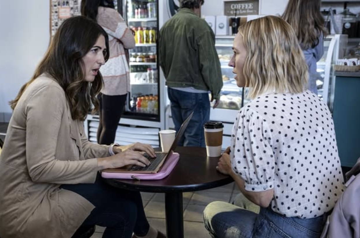 Two women chatting and working on a laptop