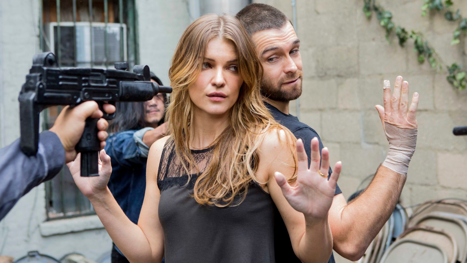 A man and woman surrounded by people with weapons